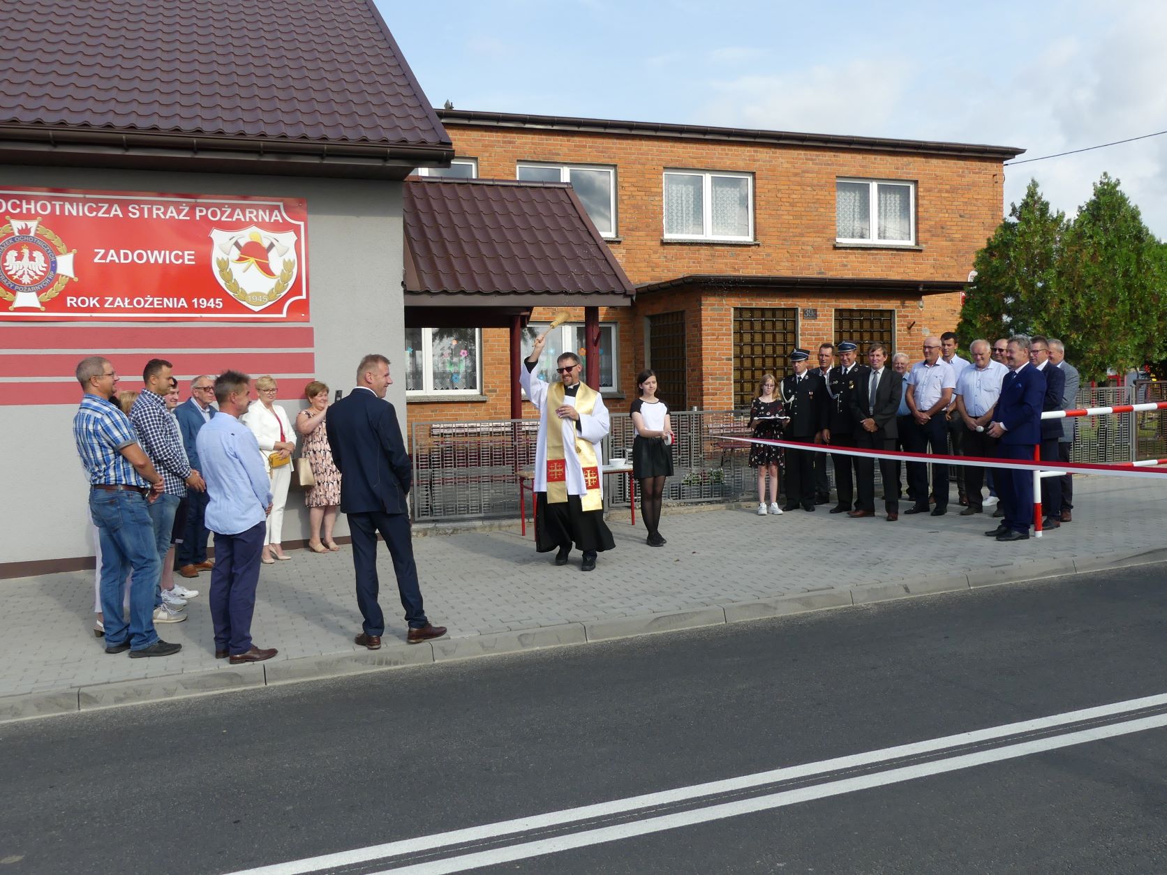 Goście biorący udział w uroczystości na tle sali OSP